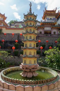 A pagoda in the centre of a water fountain in a temple complex with red lanterns, Pattaya,