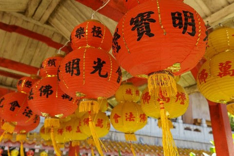 Close-up of several red lanterns with Chinese characters in a traditional temple setting, Pattaya,