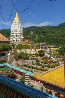 A pagoda in a temple complex with many lanterns and surrounding mountains under a blue sky,