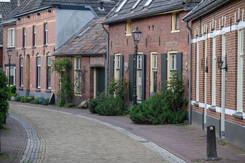 A quiet village street with rows of old brick houses, shutters and neat hedges, Bredevoort,