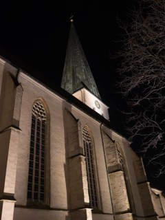 A church tower at night with Gothic architecture and dramatic lighting that emphasises the