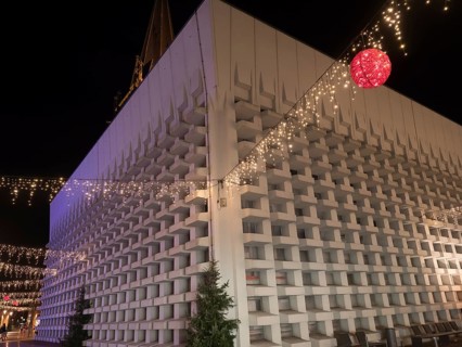 A modern building with Christmas decorations and fairy lights, suspended red ball, at night, Ahaus,
