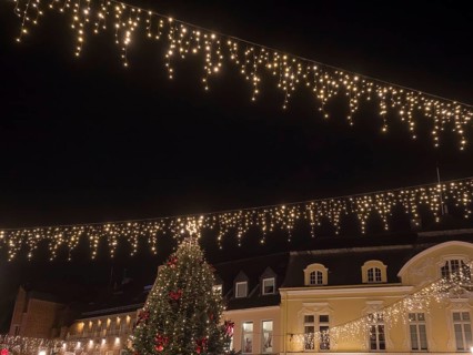 View of a festively illuminated street with fairy lights and a large Christmas tree, Ahaus,