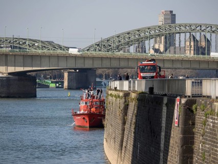 Fire boat on the river near a bridge with urban view and architectural landmarks in the background,