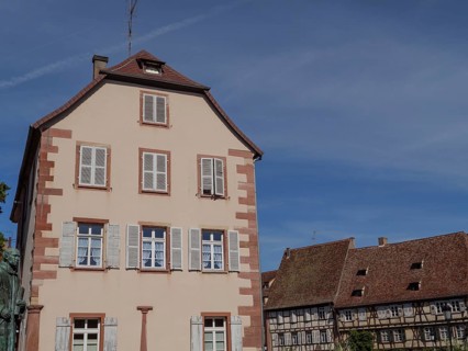 Historic building in an old town centre with white and blue shutters and half-timbered details