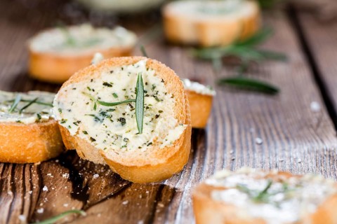 Baguette with Herb Butter and Rosemary on rustic wooden background