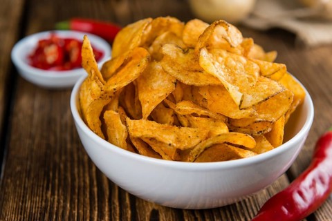 Heap of Chilli Potato Chips (selective focus) on an old wooden table