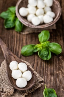 Small Mozzarella balls (on wooden background, selective focus) as close-up shot