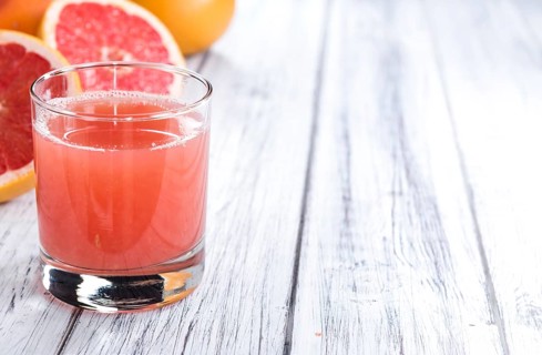 Pure Grapefruit Juice (close-up shot) on rustic wooden background