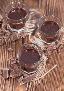 Glass with Chocolate Liqueur (close-up shot) on rustic background