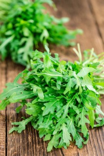 Wooden table with fresh Arugula as detailed close-up shot (selective focus)