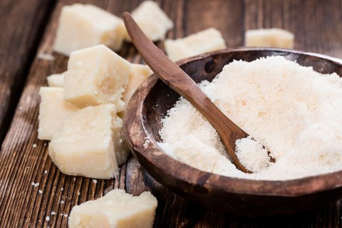 Grated Parmesan Cheese on dark wooden background (detailed close-up shot)