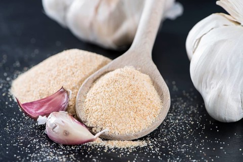 Wooden Spoon with Garlic Powder on dark background