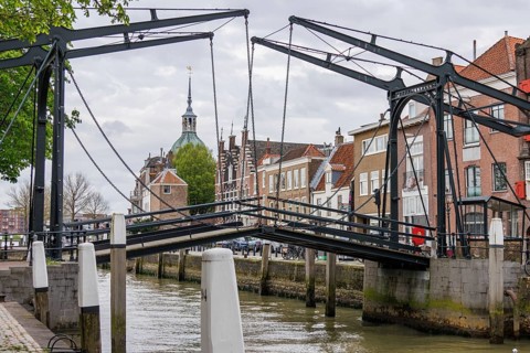 View of a historic bridge over a canal, with church tower and neighbouring houses in the