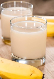 Fresh Banana Juice in a glass (detailed close-up shot) on wooden background