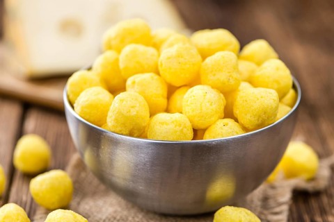 Cheese Balls on an old wooden table as detailed close-up shot (selective focus)