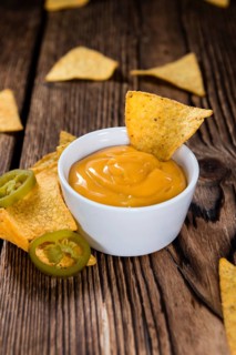 Nachos with Cheese Sauce (close-up shot) on wooden background
