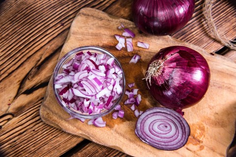 Small bowl with (diced) Red Onions on wooden background