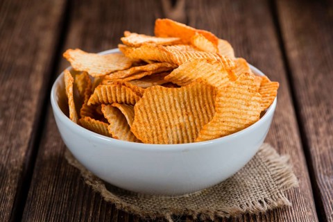 Portion of Potato Chips (rippled, selective focus) on wooden background