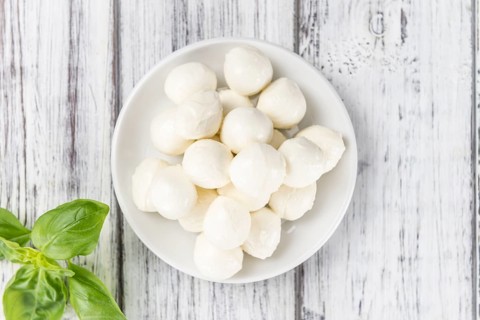 Small Mozzarella balls (on wooden background, selective focus) as close-up shot