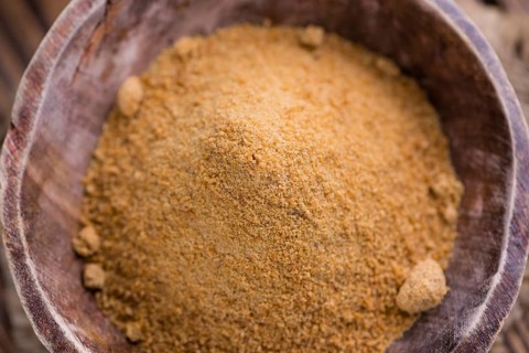 Portion of golden Coconut Sugar (selective focus) on vintage wooden background