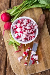 Bowl with diced Radishes (selective focus, close-up shot) on wooden background