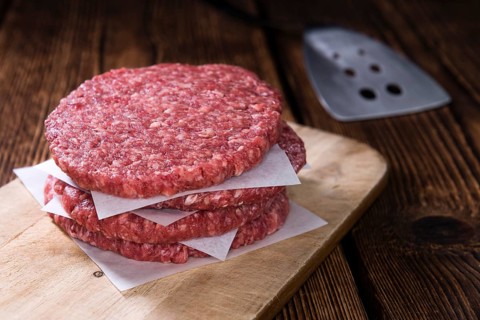 A raw Burger (minced Beef) on dark wooden background