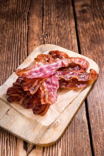 Portion of fried Bacon (selective focus) on wooden background