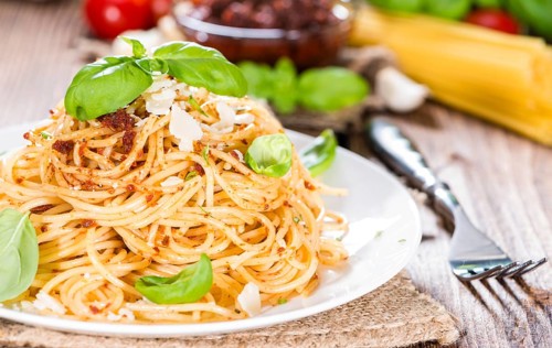 Spaghetti and Tomato Pesto on wooden background (close-up shot)