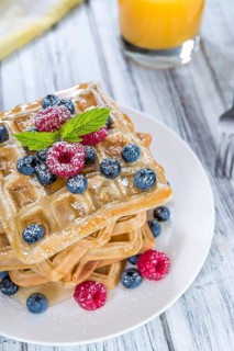 Waffles with mixed Berries and Honey (detailed close-up shot) on wooden background