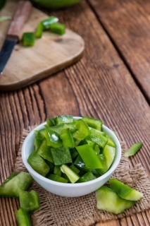 Portion of green Peppers (sliced, selective focus) on wooden background
