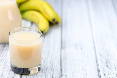 Banana juice (selective focus) on an old wooden table (detailed close-up shot)