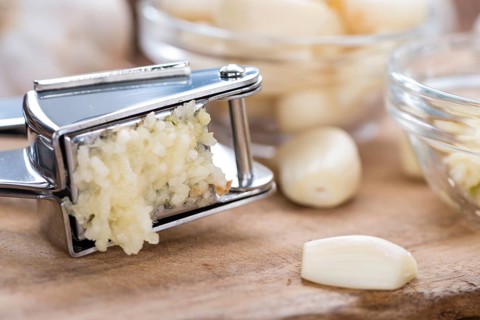 Portion of Crushed Garlic (close-up shot) on wooden background