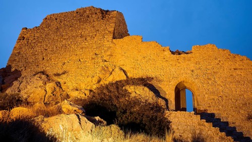 Night shot, close-up of an illuminated old castle ruin with stone steps and an archway at night,