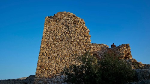 An old, ruined stone tower on a rock under a clear sky, Kritinia Castle, St John's Castle,