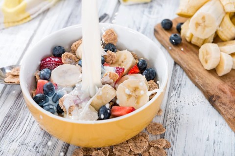 Cornflakes with fresh Fruits and Milk on a wooden table