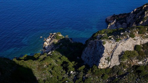 A rocky coast with deep blue sea and dense vegetation on cliffs, Kritinia Castle, St John's Castle,