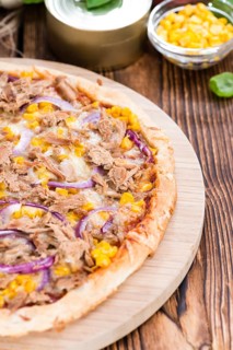 Fresh made Tuna Pizza (close-up shot) on rustic wooden background