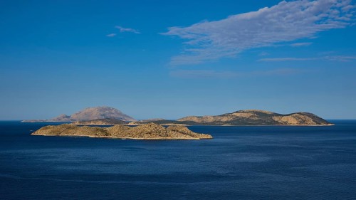 View of several islands in the blue sea under a clear sky with light clouds, Makri Island, Alimia