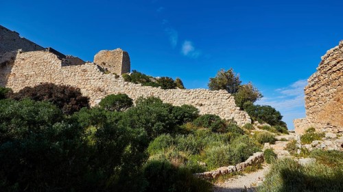 Path along the ruins of an ancient castle, surrounded by green vegetation and blue sky, Kritinia