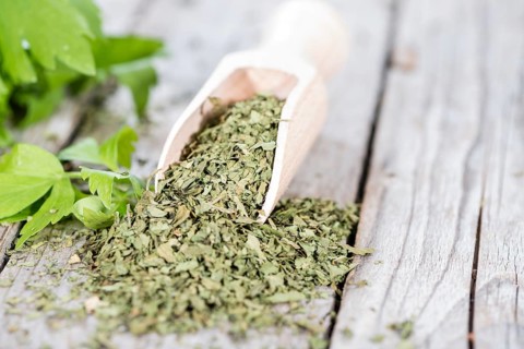 Portion of dried Lovage (detailed close-up shot) with fresh leaves on wood