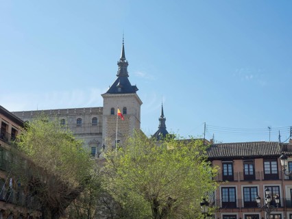 Historic tower rises above green trees, radiating a calm and spring-like atmosphere under a clear