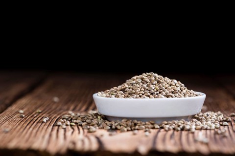 Portion of Hemp Seeds (close-up shot) on an old wooden table