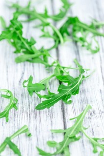 Fresh Arugula (selective focus) as detailed close-up shot on vintage background