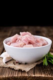 Portion of chopped Chicken Fillet (close-up shot) on wooden background