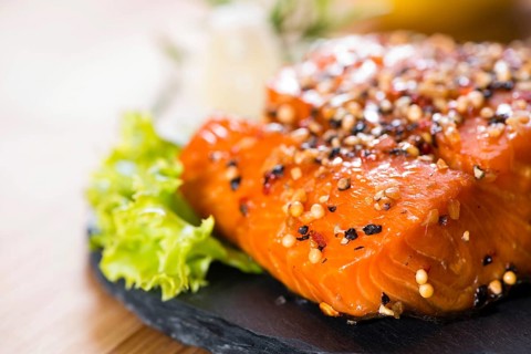 Piece of Smoked Salmon on wooden background (close-up shot)