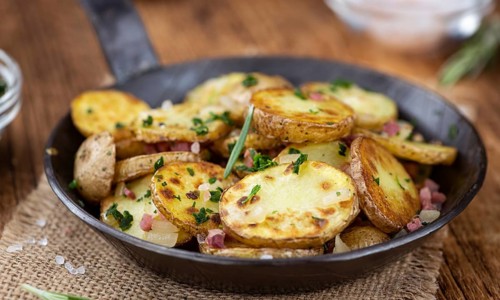 Fried Potatoes with Onions ond ham on a wooden table (selective focus)