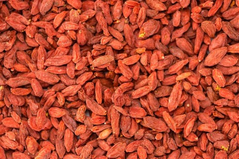 Dried Goji Berries as high detailed close-up shot on a vintage wooden table (selective focus)
