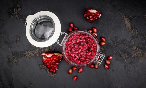 Healthy preserved Pomegranate seeds on a vintage slate slab (close-up shot, selective focus)