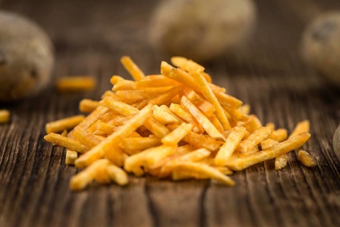 Some fried Potato Sticks (close-up shot) on an old wooden table
